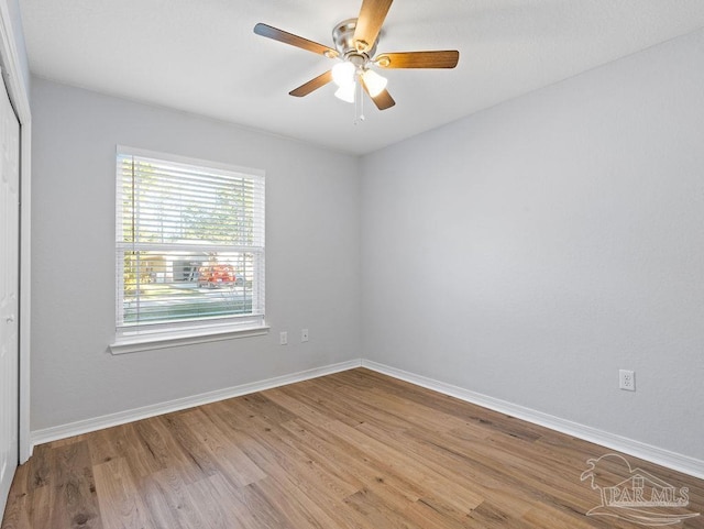 spare room featuring wood finished floors, a ceiling fan, and baseboards