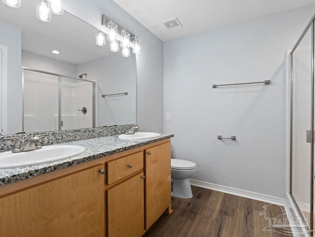 bathroom featuring a stall shower, visible vents, a sink, and wood finished floors