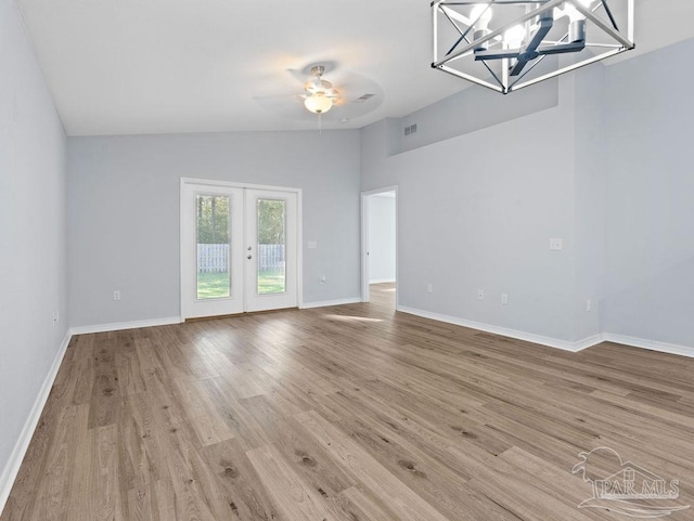 empty room featuring light wood-style floors, lofted ceiling, french doors, and visible vents