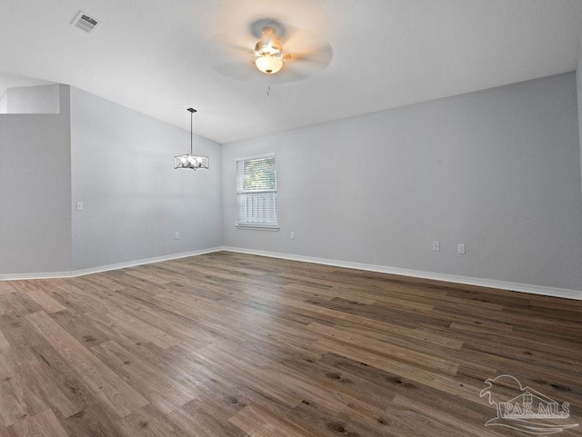 unfurnished room with baseboards, visible vents, vaulted ceiling, and wood finished floors