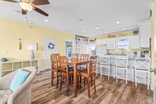 dining area with light hardwood / wood-style flooring, sink, and ceiling fan