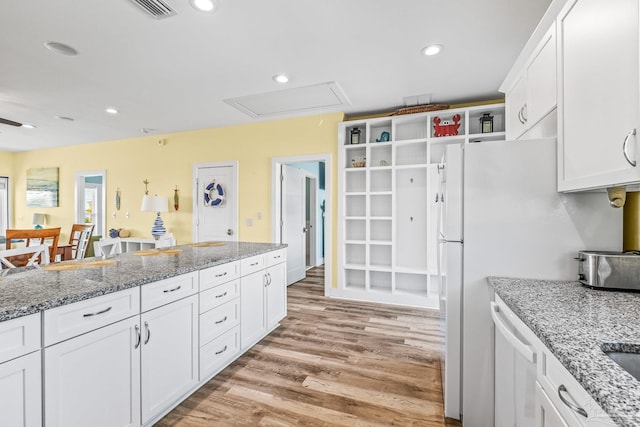 kitchen with white cabinetry, light stone countertops, light hardwood / wood-style flooring, and dishwasher