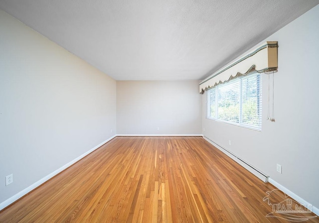 unfurnished room with hardwood / wood-style floors and a baseboard radiator