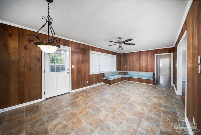 entryway featuring crown molding, wooden walls, and ceiling fan