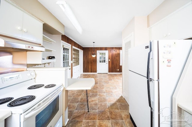 kitchen with wooden walls, hanging light fixtures, ventilation hood, white cabinets, and white appliances