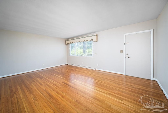 spare room featuring wood-type flooring and baseboard heating