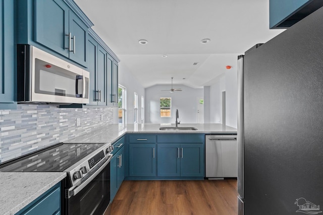 kitchen featuring sink, stainless steel appliances, tasteful backsplash, kitchen peninsula, and lofted ceiling