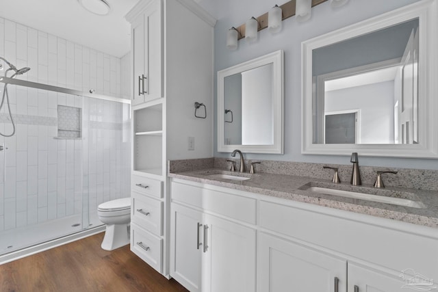 bathroom featuring hardwood / wood-style floors, vanity, toilet, and a shower with shower door