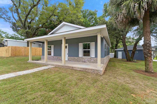 view of front of property with a front yard, a porch, and an outbuilding