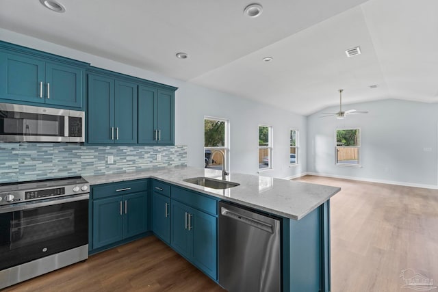 kitchen featuring sink, stainless steel appliances, kitchen peninsula, vaulted ceiling, and decorative backsplash