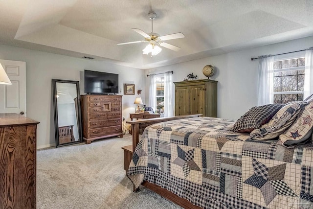 carpeted bedroom featuring a raised ceiling and ceiling fan