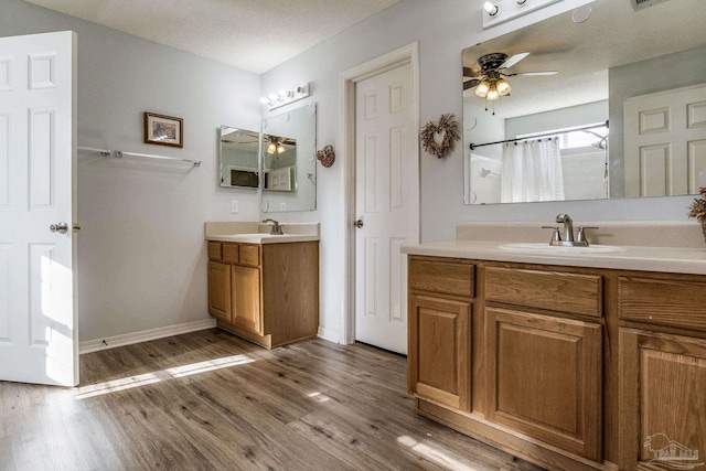 bathroom with ceiling fan, a shower with curtain, hardwood / wood-style floors, a textured ceiling, and vanity