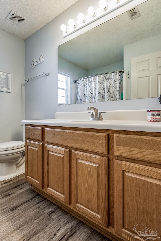 bathroom featuring a shower with curtain, a textured ceiling, toilet, vanity, and hardwood / wood-style flooring