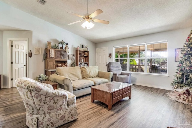 living room with hardwood / wood-style floors, a textured ceiling, ceiling fan, and lofted ceiling