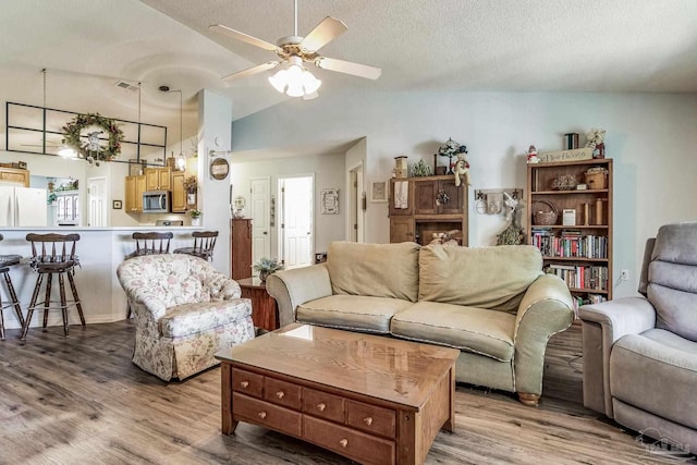 living room featuring hardwood / wood-style floors, ceiling fan, a textured ceiling, and vaulted ceiling