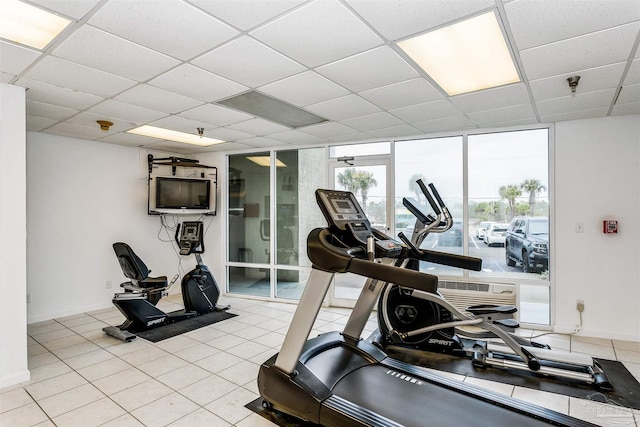 exercise room featuring a drop ceiling, light tile patterned floors, and floor to ceiling windows