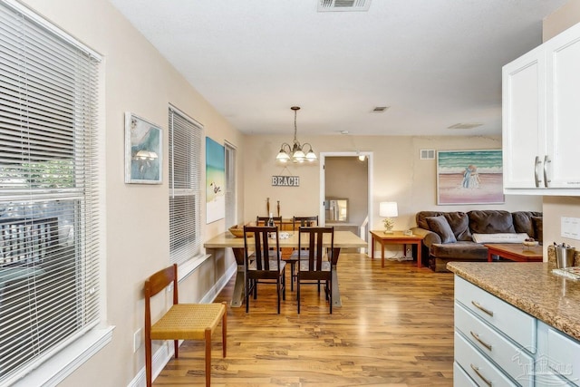 dining area featuring light hardwood / wood-style flooring and a notable chandelier