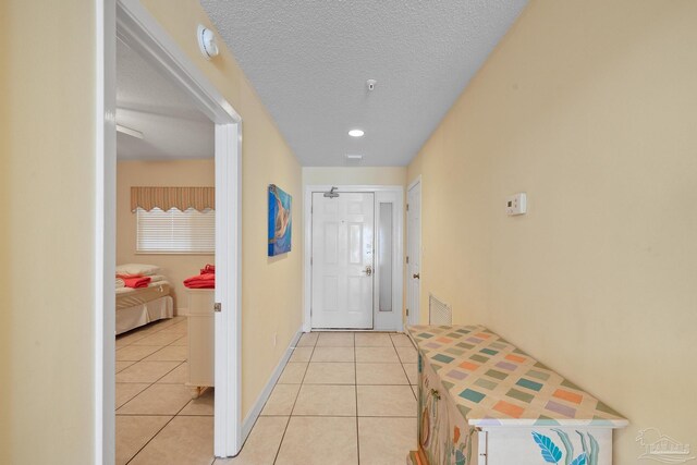 hall with light tile patterned flooring and a textured ceiling