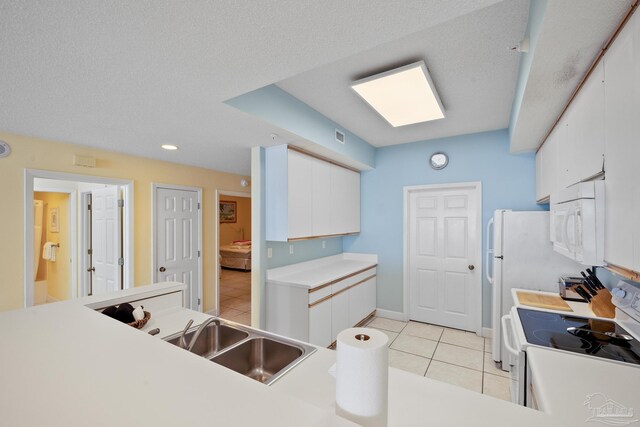 kitchen with light tile patterned flooring, white cabinetry, white appliances, a textured ceiling, and sink