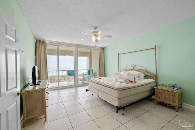 tiled bedroom with a wall of windows, a textured ceiling, access to outside, and ceiling fan