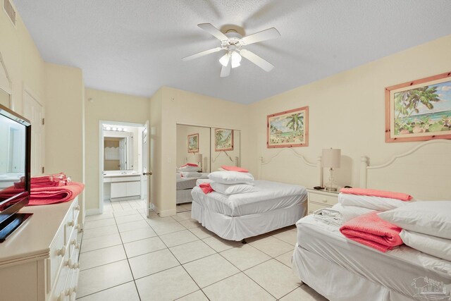 bedroom featuring a textured ceiling, ensuite bathroom, light tile patterned floors, and ceiling fan