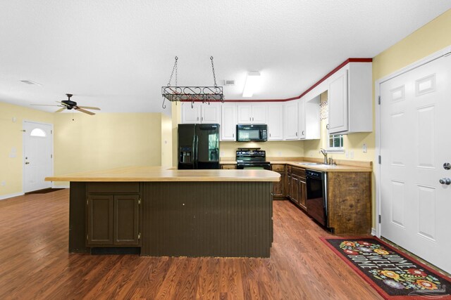 kitchen featuring black appliances, white cabinets, a center island, ceiling fan, and wood-type flooring