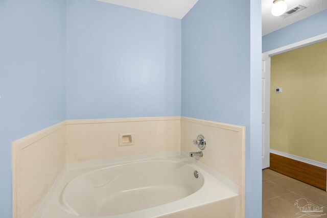 bathroom with a bathing tub, tile patterned flooring, and a textured ceiling