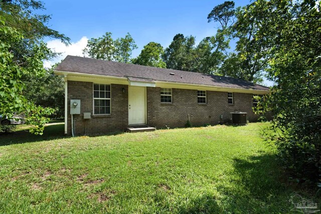 back of property with central AC unit and a yard