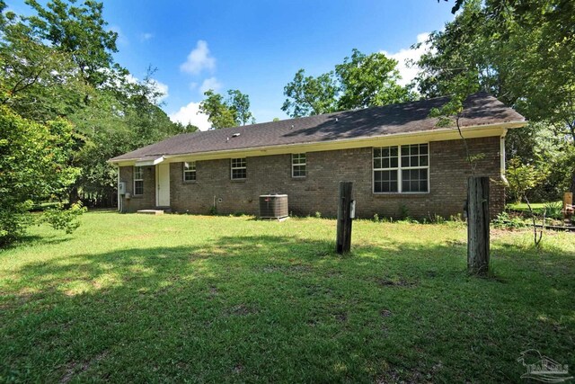 back of house with central AC unit and a lawn