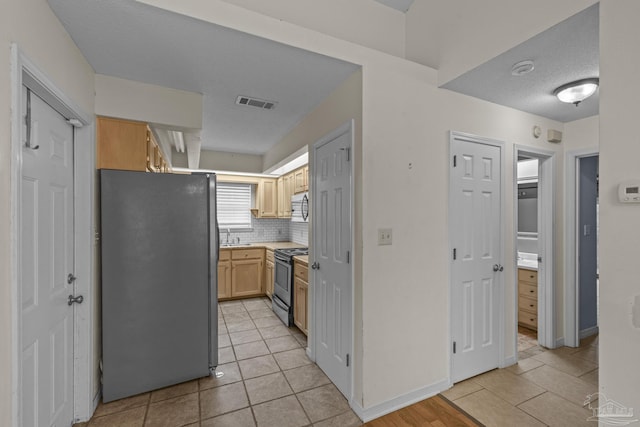 kitchen featuring visible vents, backsplash, a textured ceiling, appliances with stainless steel finishes, and light countertops