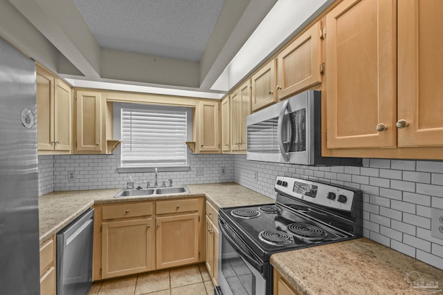 kitchen with a sink, tasteful backsplash, a textured ceiling, appliances with stainless steel finishes, and light countertops