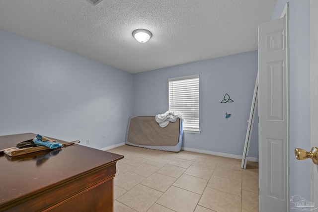 bedroom with light tile patterned floors, baseboards, and a textured ceiling