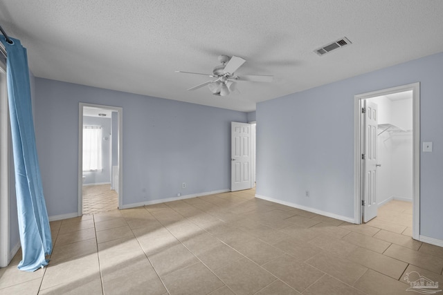 unfurnished room with baseboards, a ceiling fan, visible vents, and a textured ceiling