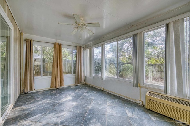 unfurnished sunroom featuring a wall unit AC and ceiling fan