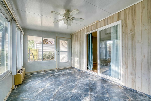 unfurnished sunroom with an AC wall unit and ceiling fan