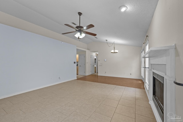 unfurnished living room with baseboards, visible vents, a fireplace, ceiling fan, and vaulted ceiling