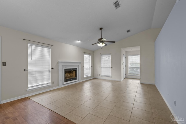 unfurnished living room with light tile patterned floors, a glass covered fireplace, a ceiling fan, and visible vents