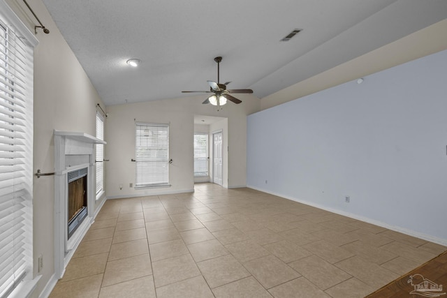 unfurnished living room featuring visible vents, lofted ceiling, light tile patterned flooring, a fireplace, and ceiling fan