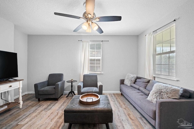 living room featuring ceiling fan, a textured ceiling, and light wood-type flooring