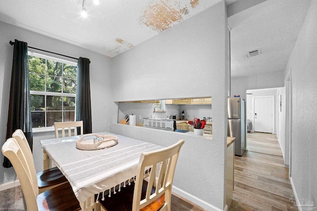 dining space featuring a textured ceiling, light wood-type flooring, and track lighting