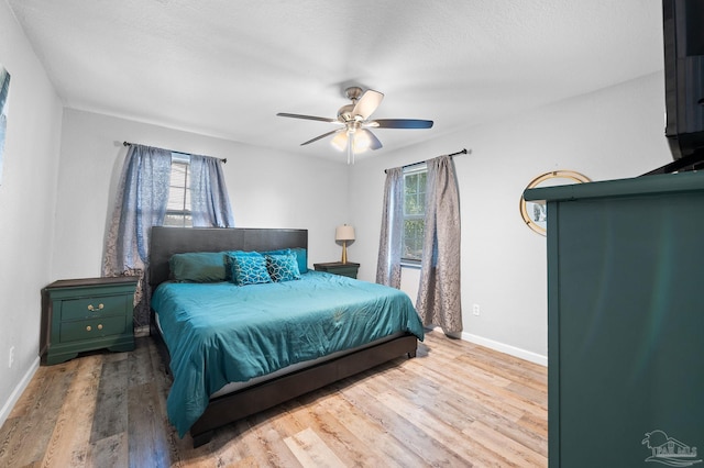 bedroom featuring multiple windows, ceiling fan, wood-type flooring, and a textured ceiling