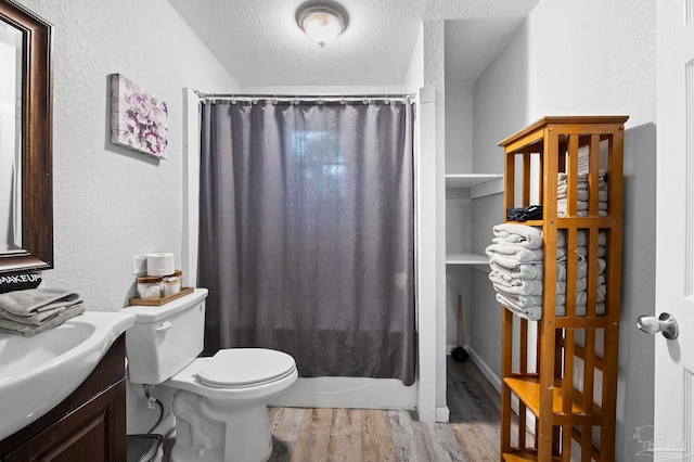 full bathroom featuring vanity, shower / bath combination with curtain, toilet, a textured ceiling, and wood-type flooring