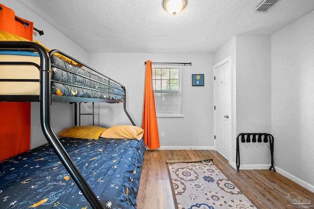 bedroom with a textured ceiling and hardwood / wood-style flooring