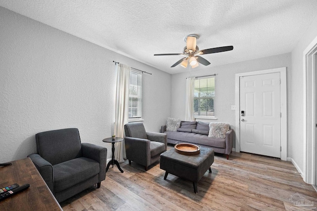 living room with a textured ceiling, light hardwood / wood-style flooring, and ceiling fan