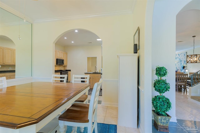 tiled dining space with crown molding, an inviting chandelier, and sink