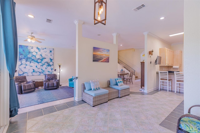 tiled living room with decorative columns, crown molding, and ceiling fan