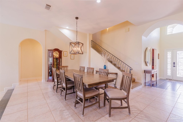 tiled dining room featuring an inviting chandelier and a high ceiling