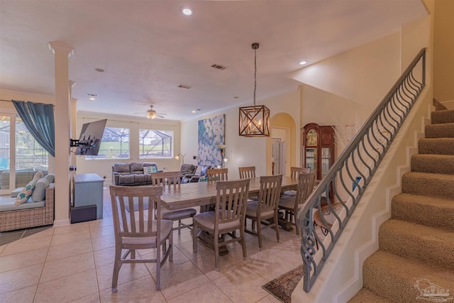 dining space featuring light tile patterned flooring, ceiling fan with notable chandelier, decorative columns, and ornamental molding