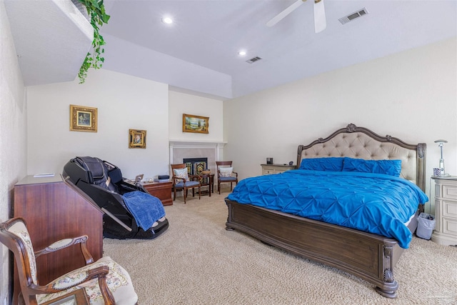 bedroom with ceiling fan, light colored carpet, and a tile fireplace