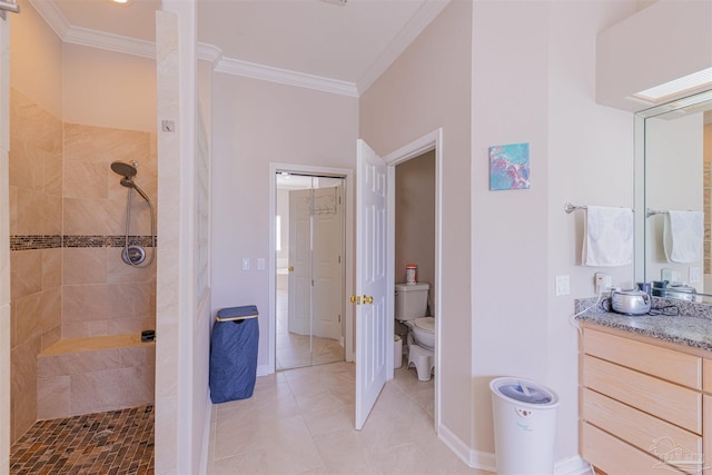 bathroom featuring a tile shower, vanity, tile patterned floors, ornamental molding, and toilet